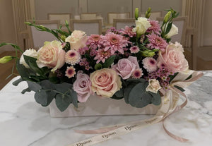 Floral arrangement on a marble table with a chandelier in the background