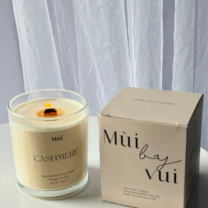 Candle and its packaging on a white surface with a light gray curtain background
