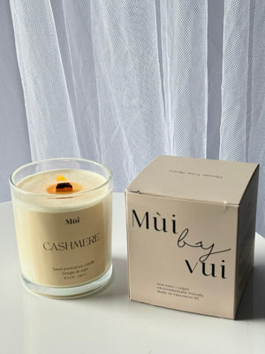 Candle and its packaging on a white surface with a light gray curtain background